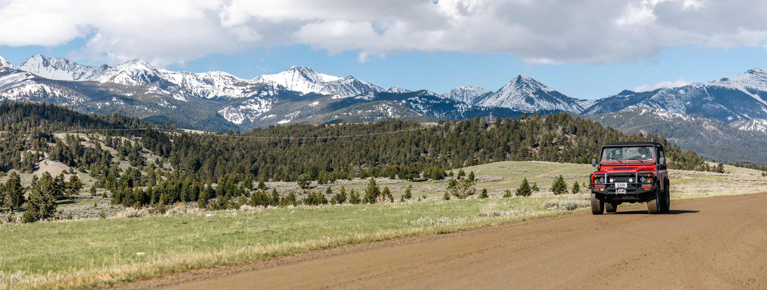 Red truck on a dirt road with mountains in the background